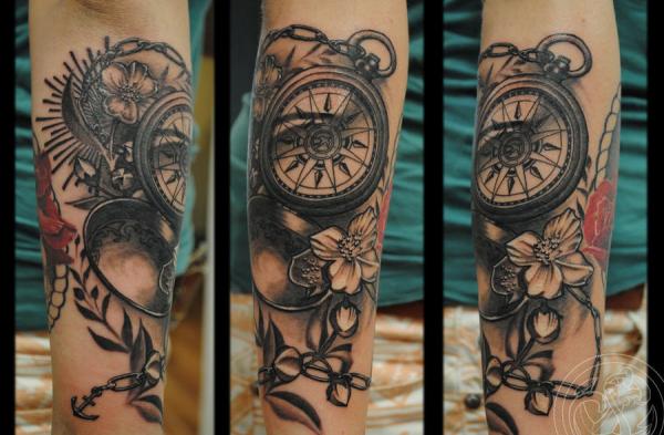 Schwarze und graue Tinte mit Kompass und Gänseblümchen am Unterarm