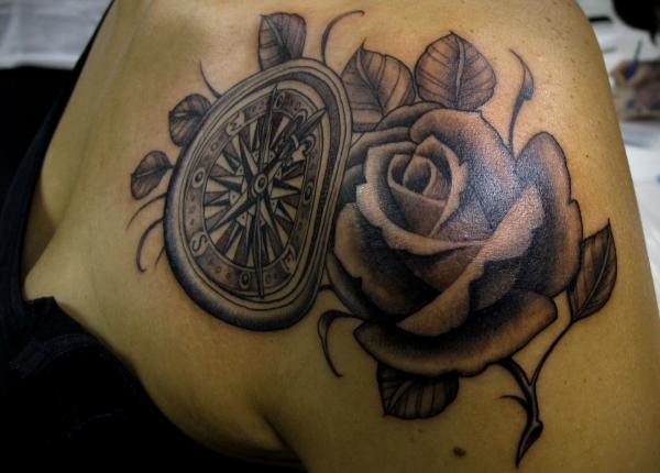Černý a šedý kompas a růžové tetování na rameni