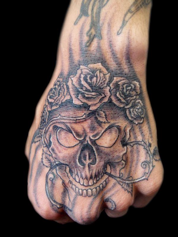 Lebka a růže s tetováním trnu na ruce