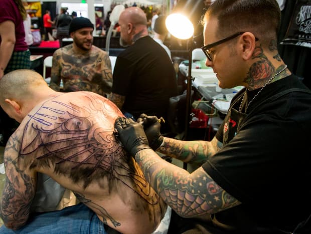 Tattoo artist Dan Smith, right, of Captured Tattoo in Tustin tetování klient Steve Brennan, který cestoval ze svého domova Washington D.C., aby Smith nechal tetovat.