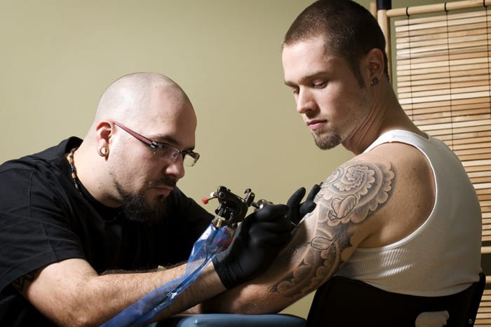 Tattooer se soustředí na to, aby někomu dal tetování na mladého muže