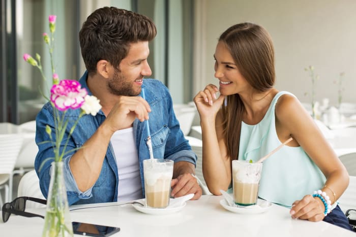 زوجان مبتسمان في المقهى يستمتعان بقضاء الوقت مع بعضهما البعض