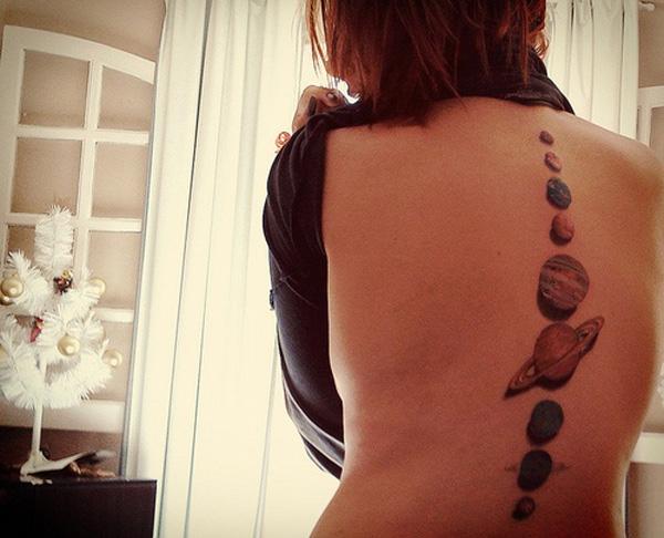 Realistické tetování vytvářející 3D efekt se sluncem a jeho planetami na páteři pro ženy