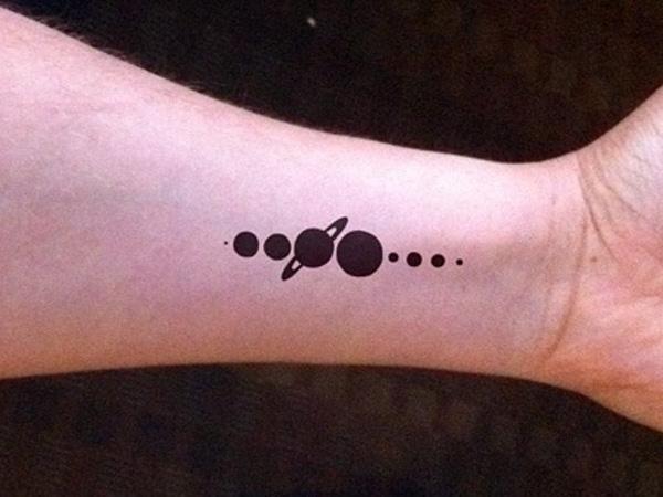 Silueta tetování s planetami v přímé linii na zápěstí