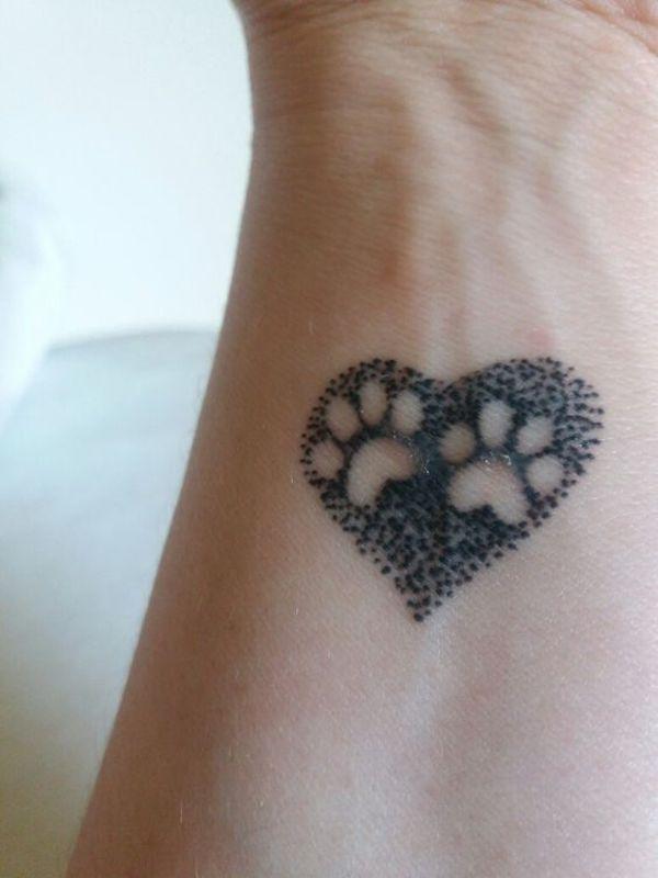 Dva otisky tlap v dotwork tetování ve tvaru srdce na zápěstí