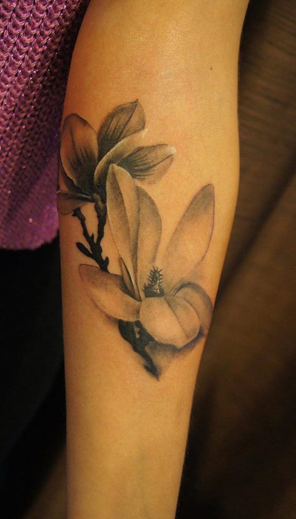 Schwarzes und weißes Tattoo mit Magnolienblume am Ärmel