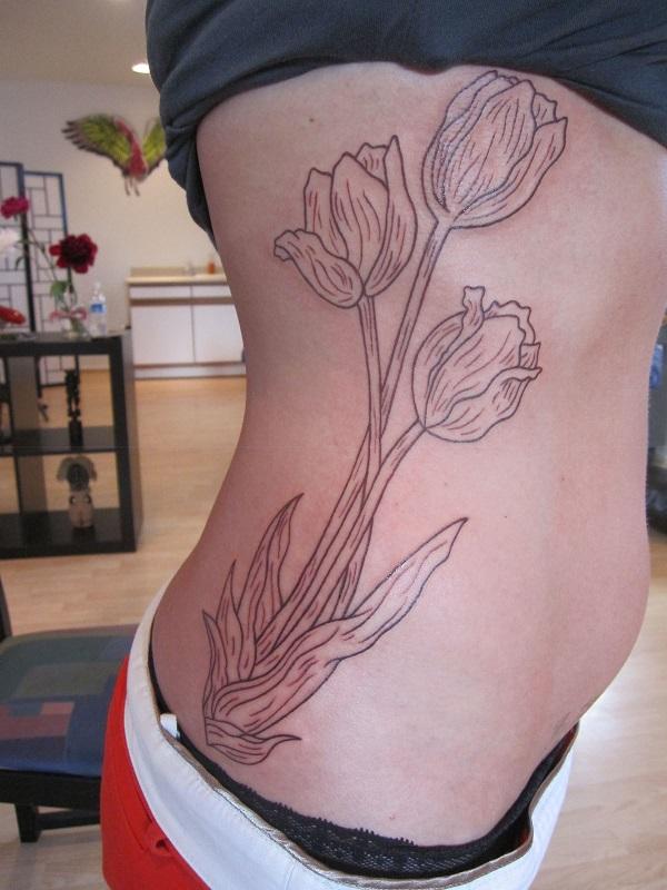 Einfaches und ordentlich aussehendes Tulpen-Umriss Tattoo an der Seite für Frauen