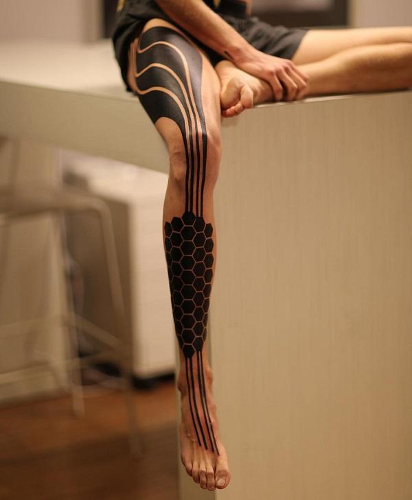 Abstraktes schwarzes Tattoo am ganzen Bein