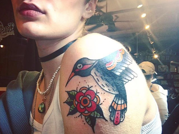 Foto přes @brendi.k.seinerNahoře má Brendi K na rameni jasný a odvážný tradiční kolibřík. Tetování provedla @cait.omen.