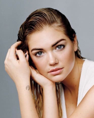 Kate Upton العارضة البالغة من العمر 23 عامًا لديها وشمان صغيران جدًا. الأول عبارة عن حدوة حصان على معصمها الأيسر والثاني صليب من الداخل من إصبعها الأوسط الأيمن. جاءت فكرة الوشم المتقاطع خلال جلسة تصوير في عام 2012 ، عندما أخذ شخص ما قلادة الصليب منها. أخبرت ايل ،