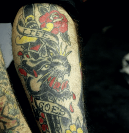 „Dieses habe ich auch auf der Warped Tour bekommen: ‚Life Goes On‘. Beatles haben einen großen Einfluss auf mich und ich wollte einfach immer eine Art Dolch/Pantherkopf. Habe das auf Warped Tour gemacht. Ich erinnere mich nicht mehr an den Namen des Künstlers, aber er hat 2 Tage lang einen Gastspot mit Oliver Peck gemacht. Und er arbeitete dort im Wohnmobil. Dieses ganze Stück dauerte ungefähr eine Stunde und 45 Minuten, bis es auf meinem Bein war. Er war gerade fertig. Es war wahrscheinlich auch das am einfachsten zu heilende Tattoo. Meine Haut wusste nicht einmal, dass es passierte, es ging so schnell. Er hatte auch eine Party, zu der er gehen wollte.“