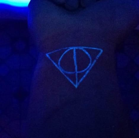 Dieser Harry-Potter-Fan ging mit einer anderen Version des Schwarzlicht-Tattoos und bekam ein UV-reaktives Stück, das vom Zeichen der Heiligtümer des Todes inspiriert wurde, drei mächtigen magischen Objekten, die angeblich vom Tod geschaffen und den drei Brüdern der Familie Peverell geschenkt wurden. Das Tattoo weist eine gerade vertikale Linie auf, die den Elder Wand darstellt, einen Kreis, der die Linie für den Auferstehungsstein schneidet, und ein Dreieck, das die beiden Symbole umschließt, die den Umhang der Unsichtbarkeit darstellen, die alle nur unter einem speziellen Schwarzlicht erscheinen.