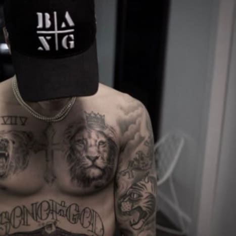Foto: Bang Bang/Instagram. Na Instagramu Bang Banga Bieber pózuje (samozřejmě bez trička) s kloboukem zakrývajícím obličej a jeho působivou sbírkou inkoustu, včetně jeho nového tetování medvěda, orla a lva. Zpěvák poprvé při turné po Novém Zélandu debutoval tetováním grizzlyho, napuštěným pod tetováním římskými číslicemi na pravé straně hrudi, a tetováním orla, vloženým mezi jeho tetování „Purpose“ a „Boží Syn“ , ale v té době byla levá strana jeho hrudníku, kde je nyní lev, nápadně bez tetování.