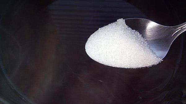 verter azúcar en una cacerola con infusión