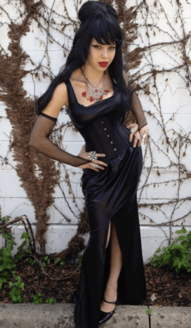 Cassandra Peterson, auch bekannt als Elvira, ist eine Horror-Schauspielerin, die durch ihr Alter Ego „Mistress of the Dark“ international bekannt wurde. Nageln Sie ihren Look mit einem verführerischen schwarzen Kleid, gekräuseltem Haar und viel Dekolleté.