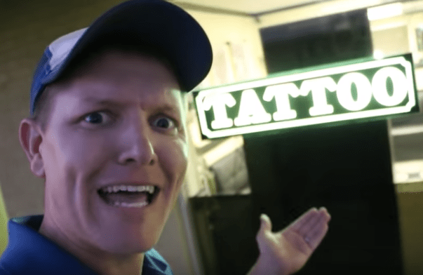 muž stojící před tetovacím salonem