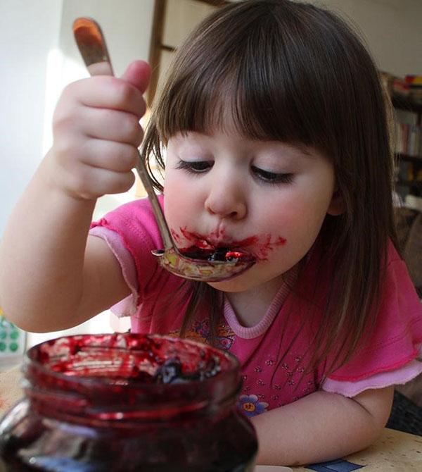 niña comiendo mermelada de frambuesa