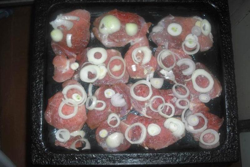 poner la carne y las cebollas en una bandeja para hornear