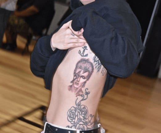 Lady GagaDas David Bowie Tattoo von Lady Gaga wurde am 13. Februar 2016 eingefärbt und zeigt ein Porträt des Ziggy Stardust Alter Egos der Sängerin, mit einem Blitz auf seinem Gesicht und einem Stern auf seinem rechten Augenlid. Das David Bowie Tribute Tattoo, das vom Star-Tattoo-Künstler Mark Mahoney gemacht wurde, befindet sich auf Lady Gagas linkem Brustkorb und wurde vom Albumcover des Sängers Aladdin Sane inspiriert.