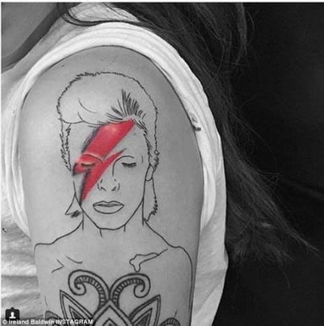 Ireland BaldwinIrland Baldwin hat sich im September 2015 ihr eigenes David Bowie Tribute Tattoo stechen lassen und ihre Tinte auf ihrer linken Schulter wurde ebenfalls vom legendären Aladdin Sane Albumcover der Sängerin inspiriert. Im Gegensatz zu Lady Gagas Tattoo, das vollständig in Grautönen gehalten ist, weist Irlands Blackwork-Tribute-Tattoo einen Farbtupfer in dem roten Blitz auf, der über Bowies Gesicht eingefärbt ist.