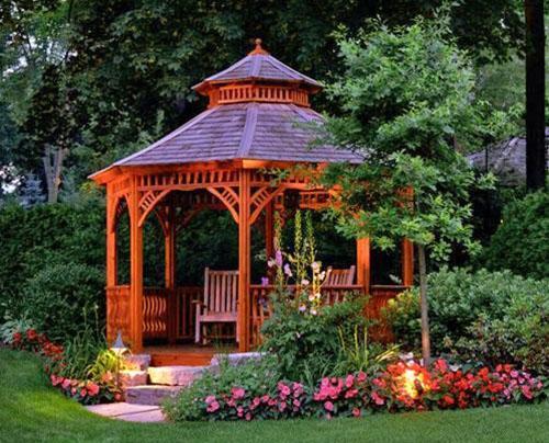 Un gazebo pour une résidence d'été en bois avec un parterre de fleurs roses