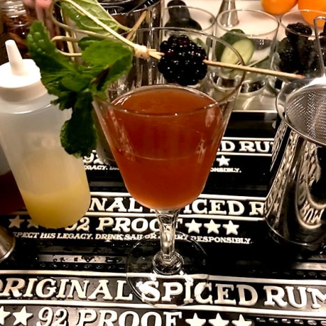 Zu guter Letzt haben wir einen Drink kreiert, der die elegante Seite von Sailor Jerry Rum herausholt. Wir begannen damit, eine saftige Brombeere in den Boden des Glases zu mischen. Dann fügten wir Turbinado Sirup, Zitronensaft und eine Handvoll Minze hinzu. Danach haben wir 3 Tropfen vietnamesische Zimttinktur hinzugefügt. Die Brombeere war eine süße Überraschung für den würzigen Sailor Jerry Rum – was diesen Drink jedoch wirklich zum Funkeln brachte, war ein kreativer Kneipentrick.