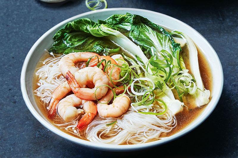 un plato de pak choi, fideos y camarones