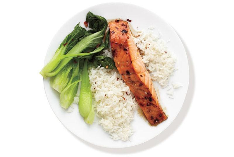 un plato de arroz, pak choy y pescado rojo