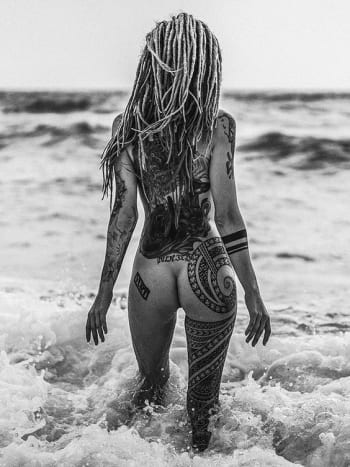 Foto přes pinterestSlunce, surf, písek, dredy a zadek zdobí kmenové tetování.