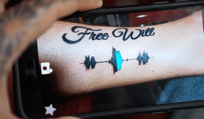 Foto über Skin Motion Sobald das Tattoo fertig ist, lädt der Künstler die Datei in das Backend von Skin Motion hoch. Innerhalb von 24 Stunden animiert Skin Motion das Overlay und fügt es der App hinzu. Der Kunde wird benachrichtigt, dass sein Tattoo jetzt „live“ ist, und wenn diese Person die App verwendet und die Kamera ihres Mobilgeräts auf das Tattoo richtet, erkennt sie die Form der Schallwelle und spielt die animierte Überlagerung ab!Die nächsten zwei Folien werden sagen Sie, wie Sie einen für sich selbst und den Videobeweis bekommen!