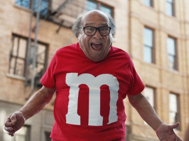 Pane bože, sny se splnily. Danny Devito prožil naši fantazii tím, že se stal lidským M&M. Veličenstvo z oblíbených amerických cukrovinek ještě jednou.