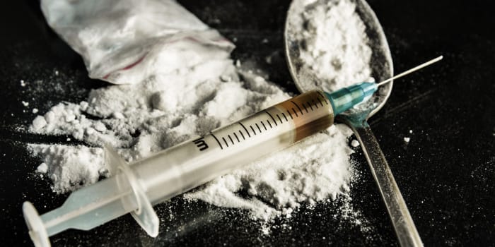 Drogenspritze und gekochtes Heroin auf Löffel