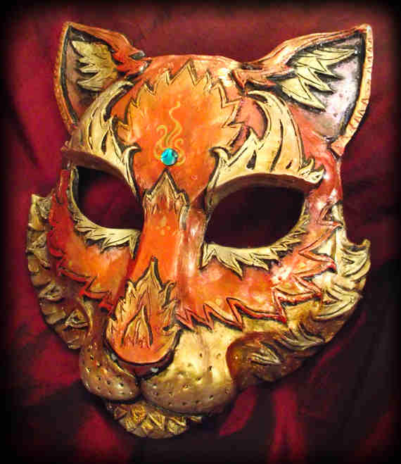 CAT MASK قناع مصبوب. مرسومة باليد ومنحوتة باليد. هذا نوع من موضوع النار يحدث مع لمعان ذهبي إلى اللون البرتقالي. الجوهرة قطعة من أذن البحر الأزرق. يغطي هذا القناع معظم الوجه. العرض عبر العينين تقريبًا 6