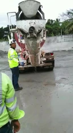Dva pracovníci trpělivě čekají, až se vyčistí vše, co ucpává cementový žlab.